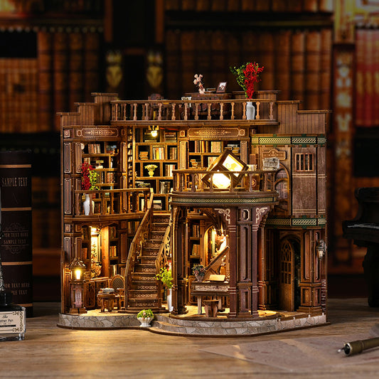 Vue d'ensemble d'une maquette en bois d'une bibliothèque ancienne illuminée. On y voit des étagères de livres, un grand escalier central, un piano à queue miniature au rez-de-chaussée et des balcons en bois sculpté, le tout baigné dans une lumière dorée chaleureuse.
