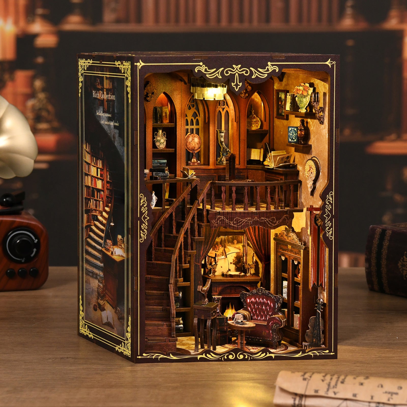 Miniature en bois d'une bibliothèque classique à deux étages insérée dans un coffret, présentant un escalier courbe, des étagères remplies de livres miniatures et un fauteuil près d'une cheminée, le tout illuminé par une lumière tamisée