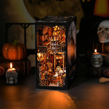 Maquette de serre-livres miniature 'Dark Family' sur le thème gothique d'Halloween, avec un manoir hanté illustré sur le côté et un intérieur de bibliothèque ancienne richement détaillé et éclairé.