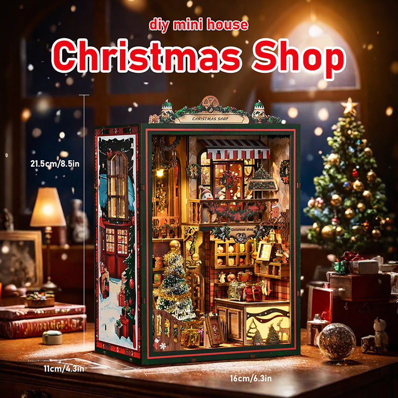 Maquette DIY Book Nook 'Christmas Shop' en bois représentant une boutique de Noël chaleureuse. L'intérieur comprend un sapin enneigé scintillant, un bonhomme de neige sur un balcon, des cadeaux miniatures et un éclairage LED jaune créant une ambiance de village de Noël magique