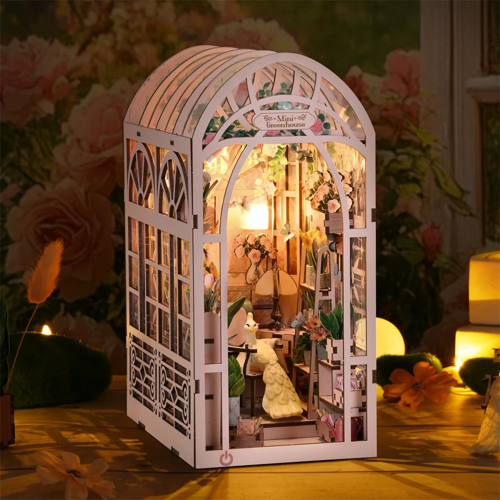 Vidéo de présentation du Book Nook 'Mini Greenhouse' montrant le montage d'une serre miniature rose avec éclairage LED. La séquence détaille les accessoires intérieurs comme un paon blanc, un gramophone, un chevalet et de nombreuses plantes fleuries.