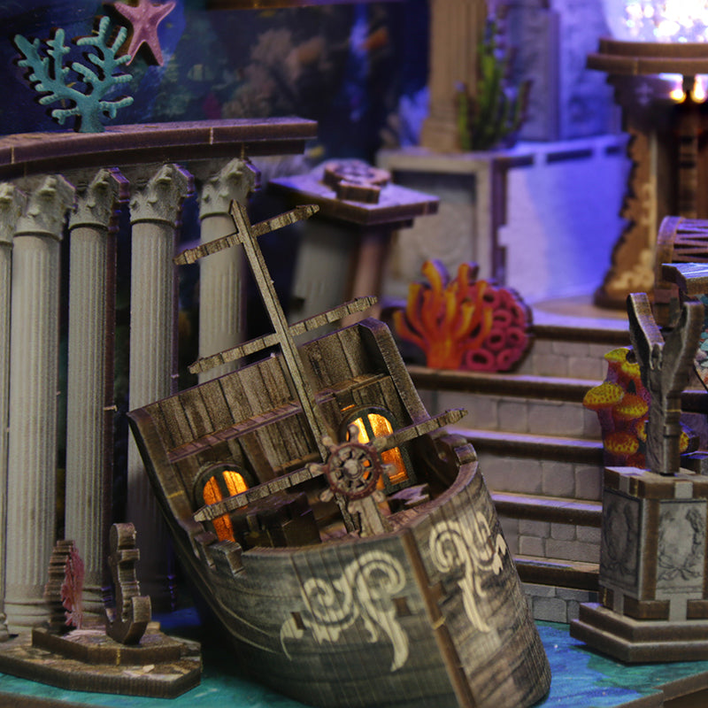 Maquette en bois miniature d'une épave de galion rétroéclairée dans un décor d'Atlantide avec colonnes grecques et coraux