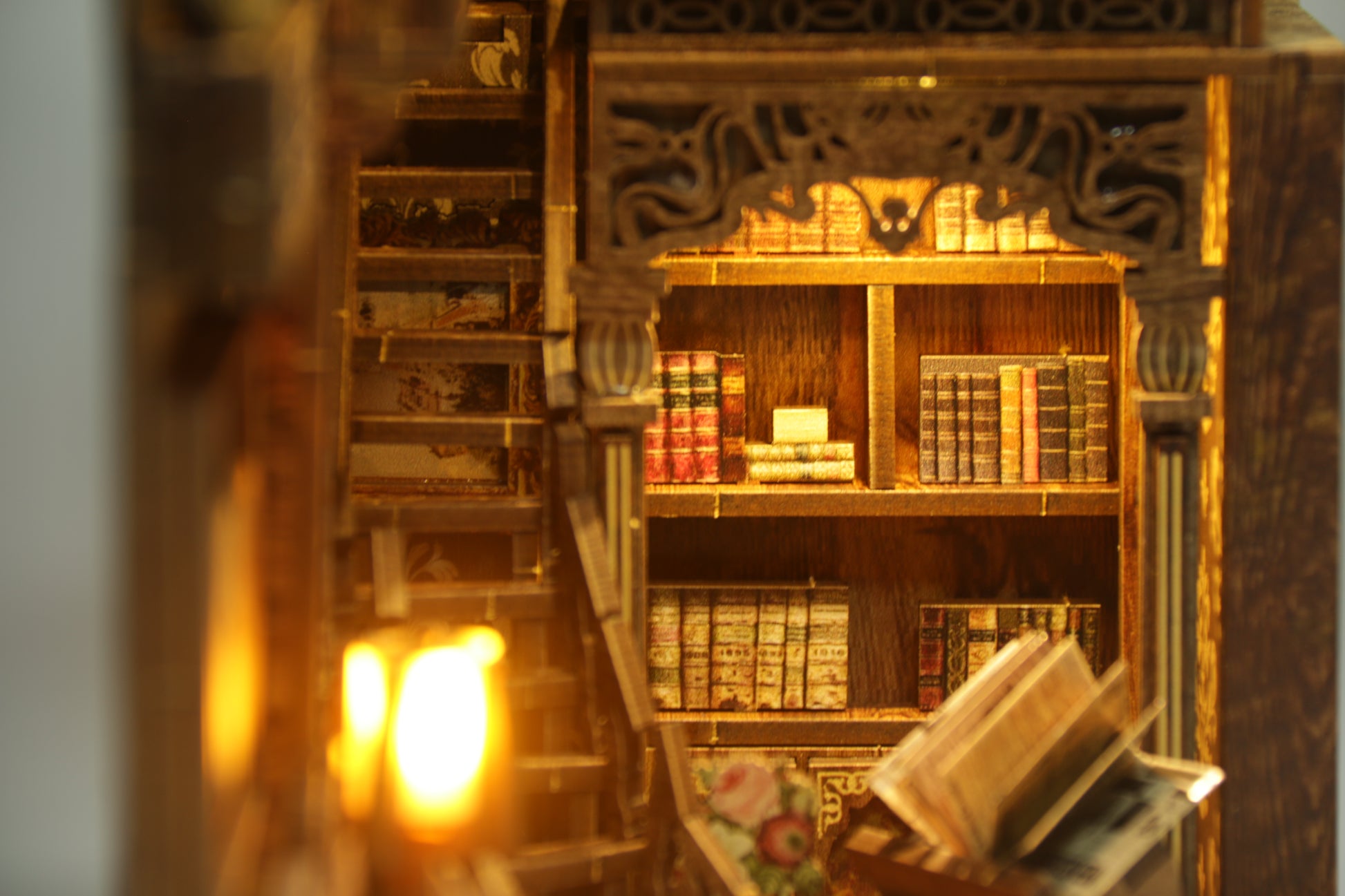 Gros plan sur les détails d'un Book Nook en bois : étagères de livres miniatures, fenêtre éclairée et balcon sculpté au laser.