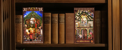 Deux serre-livres décoratifs Book Nook "Cat Affairs Bureau" installés sur une étagère en bois entre des livres anciens, avec éclairage LED nocturne chaleureux.