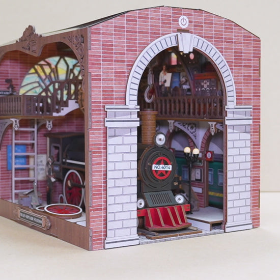 Gros plan sur les détails d'un book nook Cathédrale : figurine de Jésus-Christ, vitraux d'anges miniatures, allée centrale avec bancs et décoration florale.