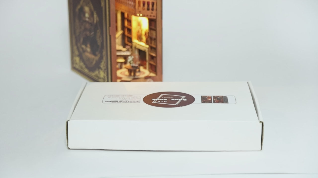 Présentation du kit DIY Book Nook 'Grimm’s Small Building'. La vidéo montre le déballage de la boîte, les pièces en bois découpées au laser, le manuel d'assemblage et le résultat final : une bibliothèque miniature rétro éclairée avec un piano, un escalier et des étagères de livres, parfaitement intégrée entre de vrais livres sur une étagère.