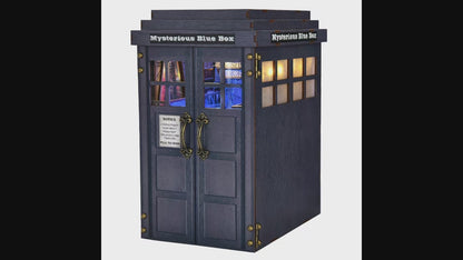 Kit Book Nook DIY "Mysterious Blue Box" en bois, inspiré d'une cabine de police bleue. L'intérieur détaillé s'éclaire d'un bleu intense via un interrupteur tactile, révélant une salle de contrôle futuriste avec des figurines, une console centrale et des bibliothèques miniatures. Dimensions : 18 x 13 x 24 cm.