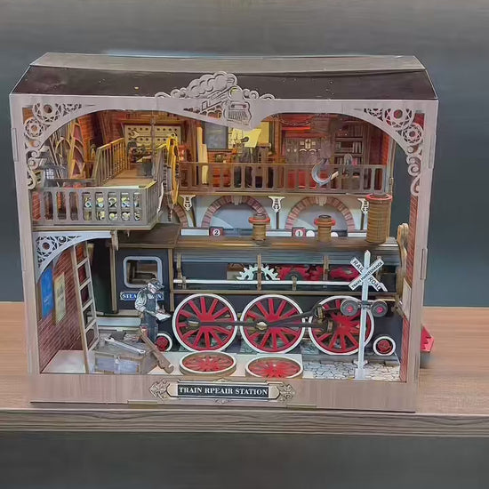 Vidéo de présentation du book nook Train Repair Station : gros plan sur une locomotive à vapeur miniature, engrenages mobiles, éclairage LED et atelier ferroviaire détaillé en bois.