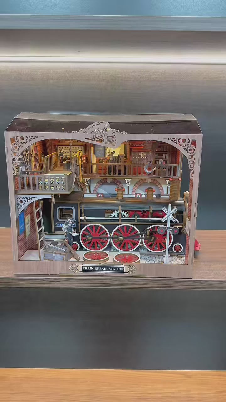 Vidéo de présentation du book nook Train Repair Station : gros plan sur une locomotive à vapeur miniature, engrenages mobiles, éclairage LED et atelier ferroviaire détaillé en bois.