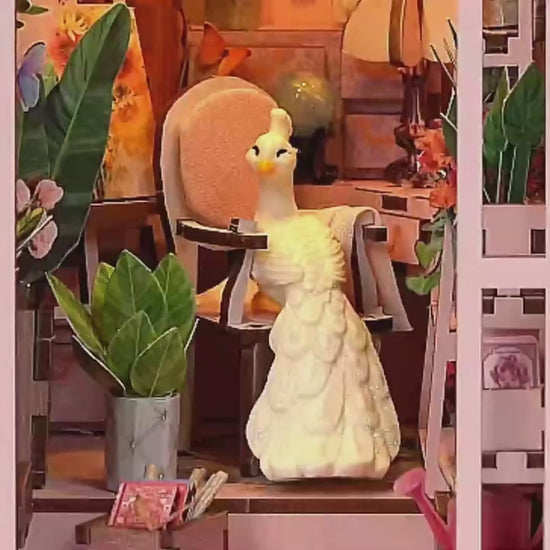 Vidéo de montage et présentation d'un Book Nook 'Mini Greenhouse' : serre miniature en bois rose avec éclairage LED, paon blanc décoratif et nombreuses plantes miniatures. Démonstration de l'assemblage et du rendu final dans une bibliothèque.