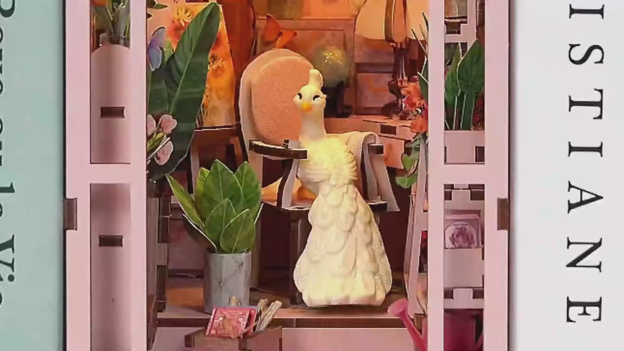 Vidéo de montage et présentation d'un Book Nook 'Mini Greenhouse' : serre miniature en bois rose avec éclairage LED, paon blanc décoratif et nombreuses plantes miniatures. Démonstration de l'assemblage et du rendu final dans une bibliothèque.