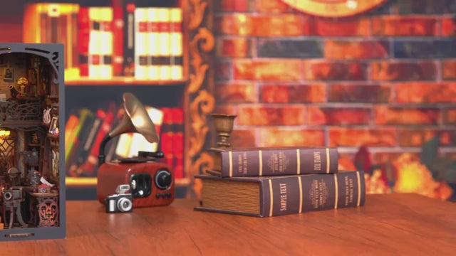 Maquette de serre-livres (Book Nook) sur le thème d'un studio photo vintage et chambre noire, avec des étagères d'appareils photo miniatures, un lustre rétro et une façade illustrée du Tower Bridge de Londres.