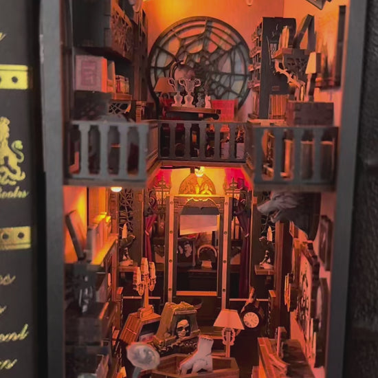 Vidéo immersive du Book Nook 'Dark Family' révélant un intérieur gothique détaillé avec une main de la Famille Addams, un cercueil, une fenêtre en toile d'araignée et des portraits anciens sous une lueur jaune chaleureuse.