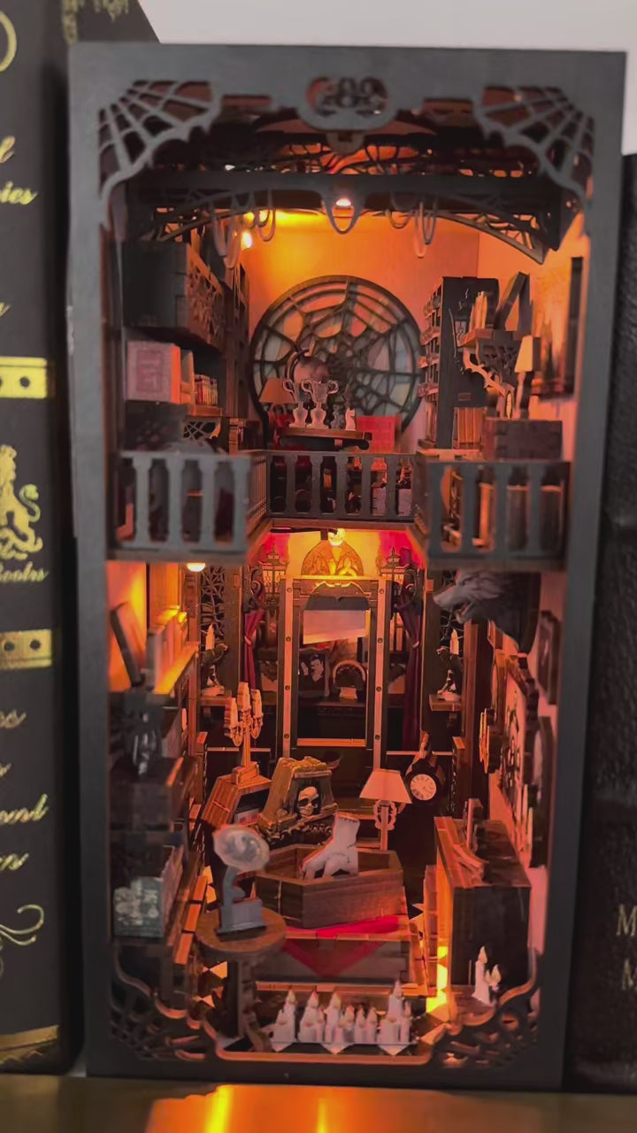 Vidéo immersive du Book Nook 'Dark Family' révélant un intérieur gothique détaillé avec une main de la Famille Addams, un cercueil, une fenêtre en toile d'araignée et des portraits anciens sous une lueur jaune chaleureuse.